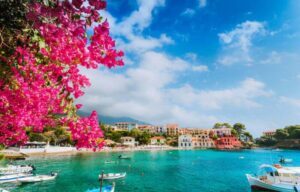 Cenário bonito da vila de Assos emoldurado com ramo da flor fúcsia magenta da flor goya copastur viagens de luxo alto padrao