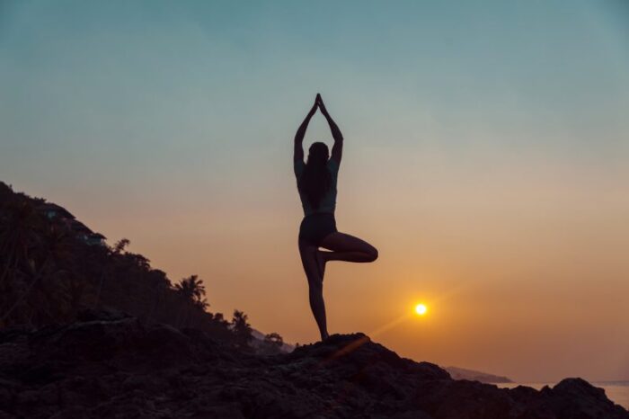 Mulher praticando yoga na praia